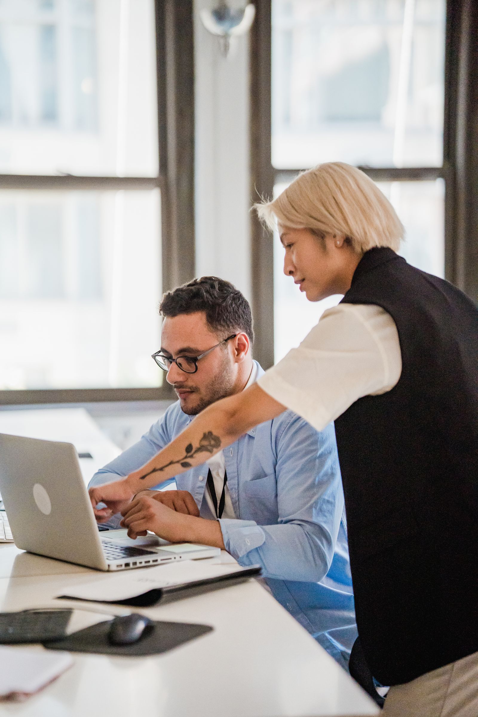 Colleague handing a laptop to another employee across a desk